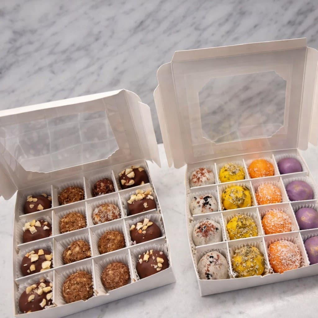 Two open boxes of hand-rolled Aum Bites on a marble counter